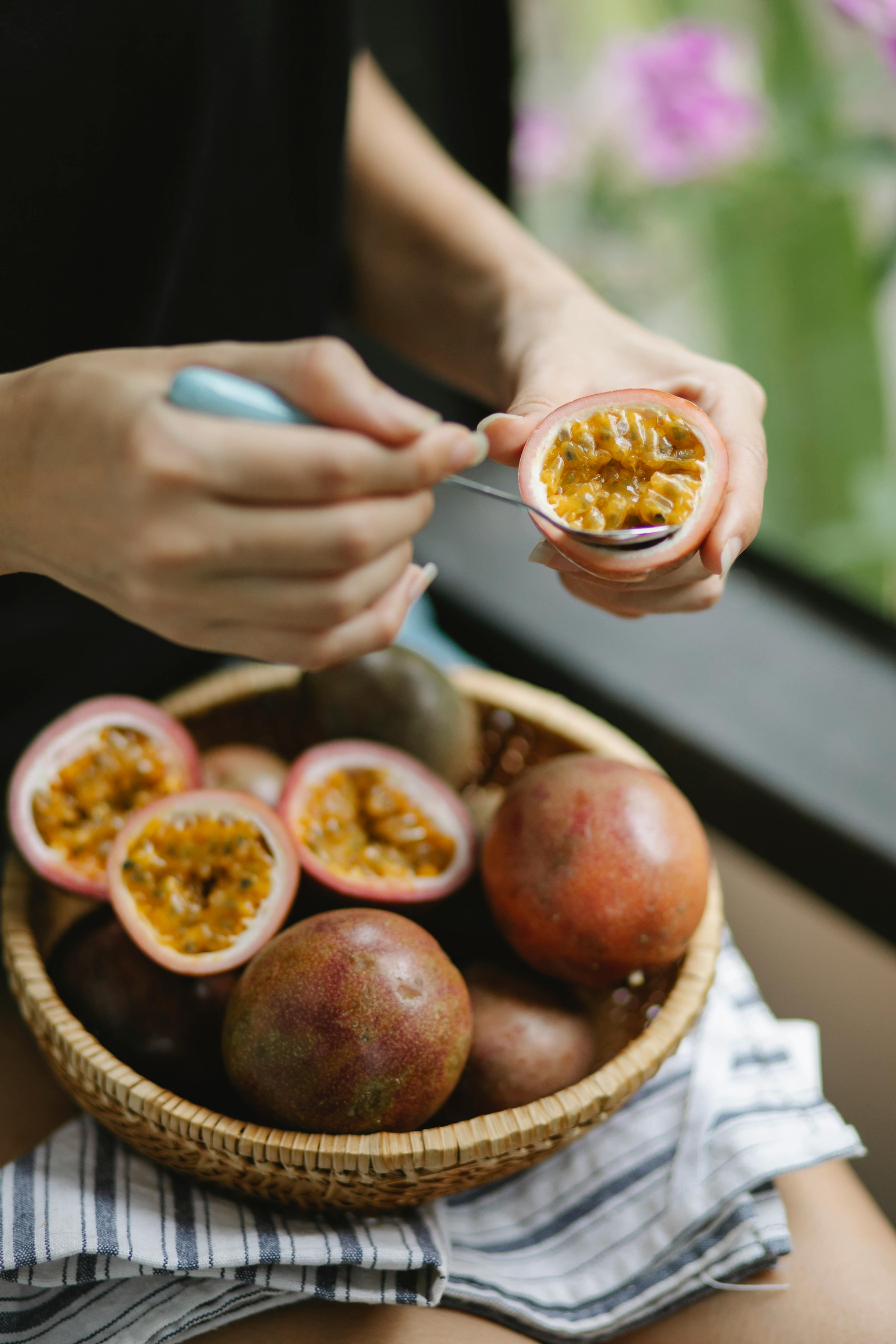Close-up of a spoon scooping golden passionfruit pulp and seeds from a halved fruit
