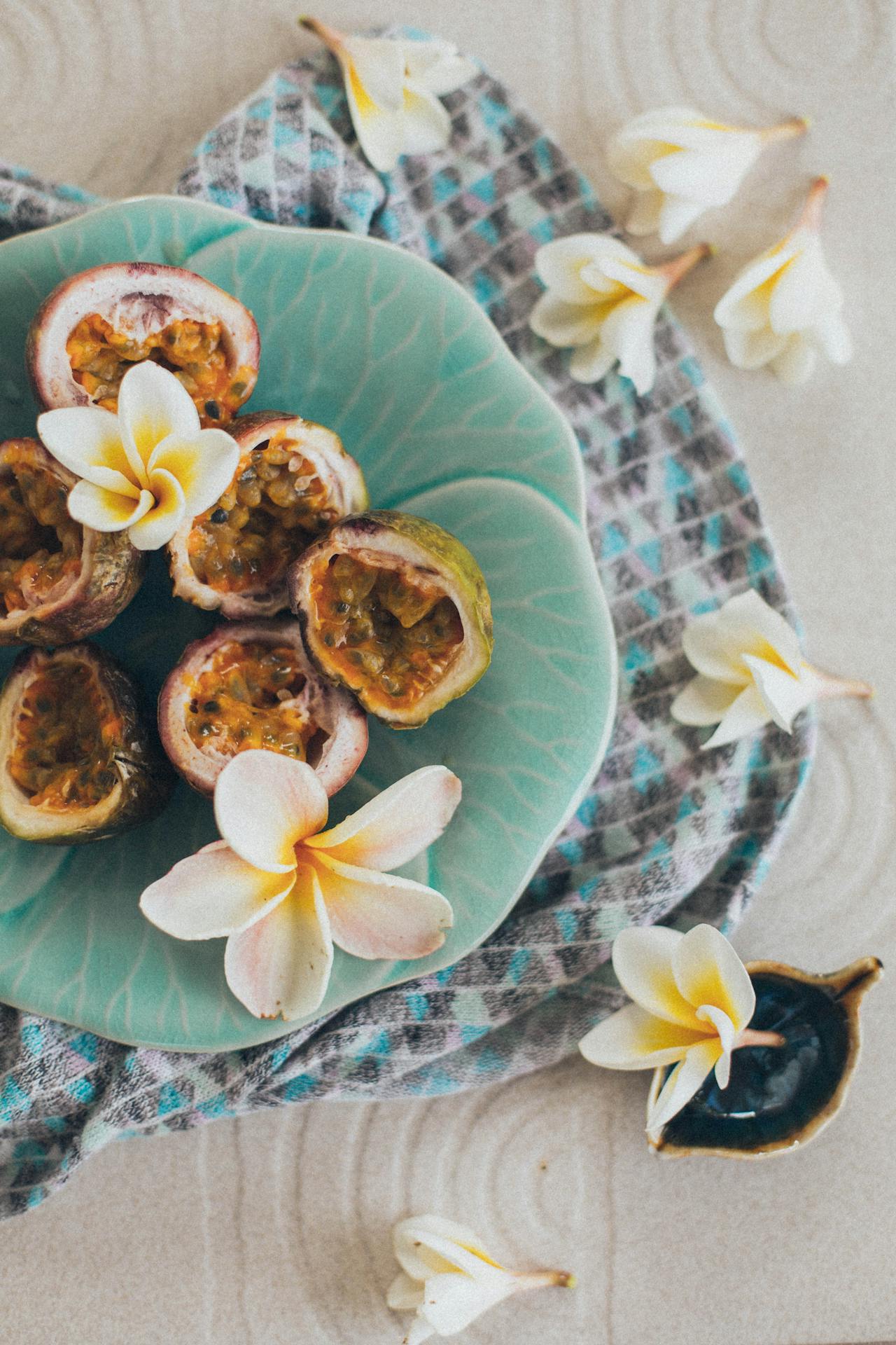 Passionfruit laid on a plate and tropical flowers symbolizing wellness and relaxation